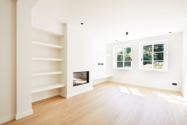 Wohnzimmer mit Kamin, eingebauten Regalen, Holzboden und großen Fenstern – Stadthaus Fafnerstraße, München · Nymphenburg