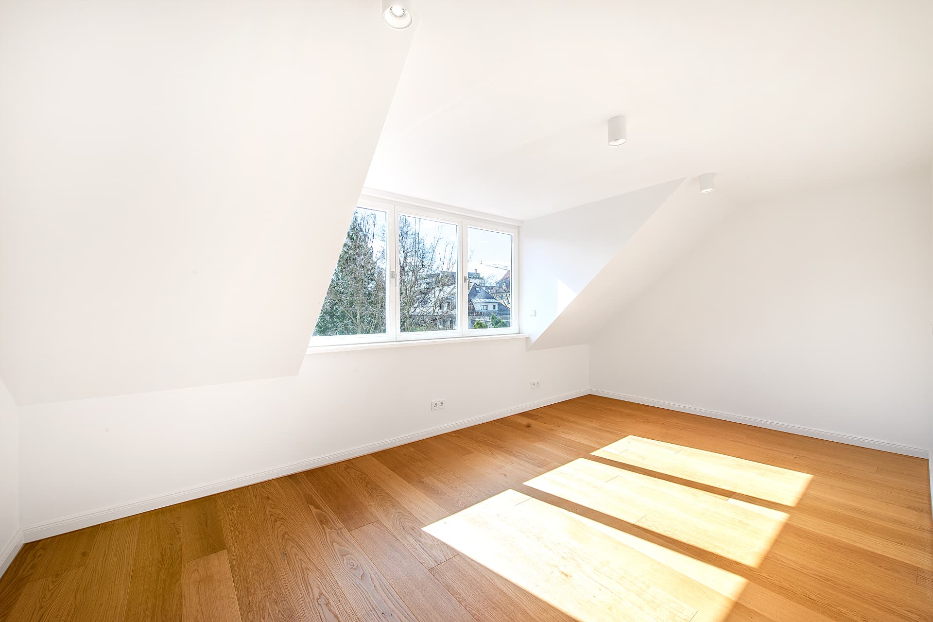 Lichtdurchflutetes Zimmer im Dachgeschoss mit Dachschrägen und Holzboden – Stadthaus Virchowstraße, München · Schwabing