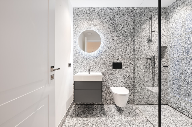 Bad im Untergeschoss mit gemusterten Fliesen, rundem Spiegel und verglaster Dusche – Villa Konitzer Straße, München · Bogenhausen