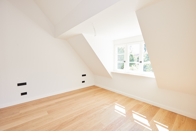 Schlafzimmer im Dachgeschoss mit Dachschrägen, breitem Fenster und Holzboden – Stadthaus Fafnerstraße, München · Nymphenburg