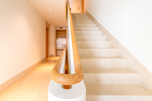 Helles Treppenhaus mit geschwungenem Holzhandlauf und hellen Stufen – Haus Pagodenburgstraße, München · Obermenzing