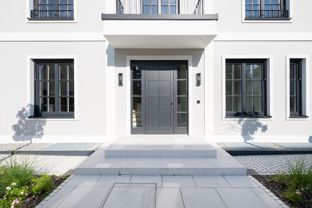 Hauseingang mit dunkler Eingangstür, heller Fassade und gepflastertem Zugangsweg – Villa Konitzer Straße, München · Bogenhausen