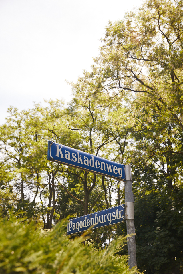 Straßenschilder Kaskadenweg und Pagodenburgstraße vor grünen Baumkronen – Haus Pagodenburgstraße, München · Obermenzing