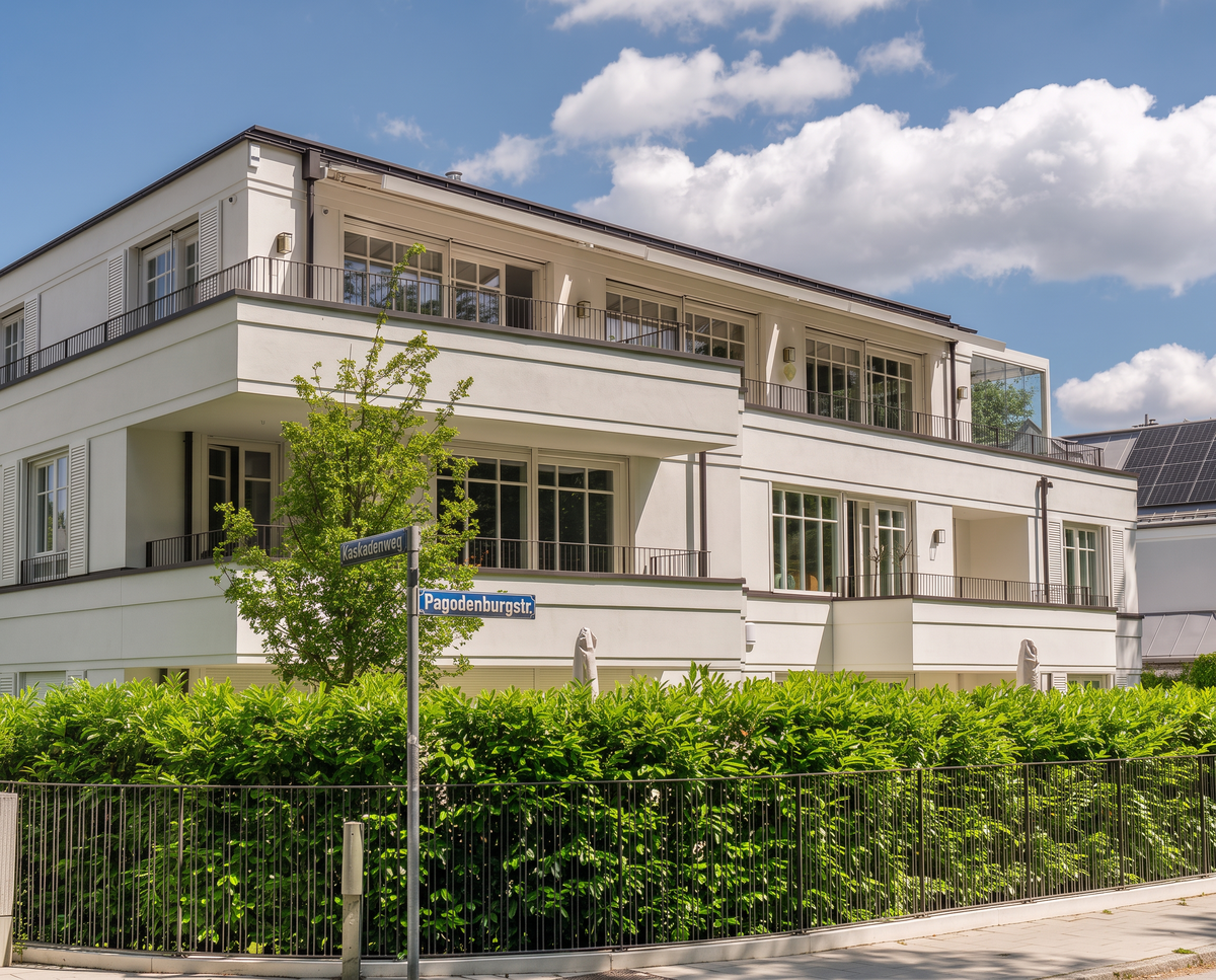 Straßenansicht mit heller Fassade, Balkonen und Hecke am Kaskadenweg – Haus Pagodenburgstraße, München · Obermenzing