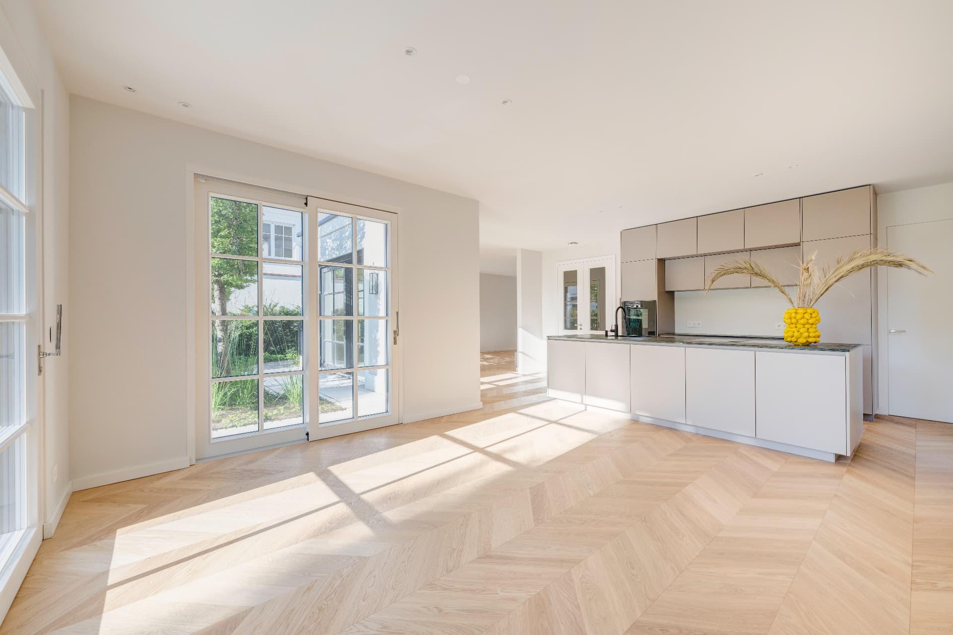 Offene Küche mit Kochinsel, hellen Schränken und bodentiefen Fenstern zum Garten – Villa Konitzer Straße, München · Bogenhausen